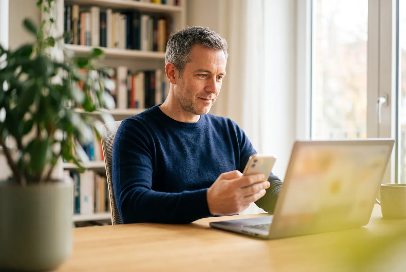 A man comparing an AI assistant's answer on his phone with search results on his laptop