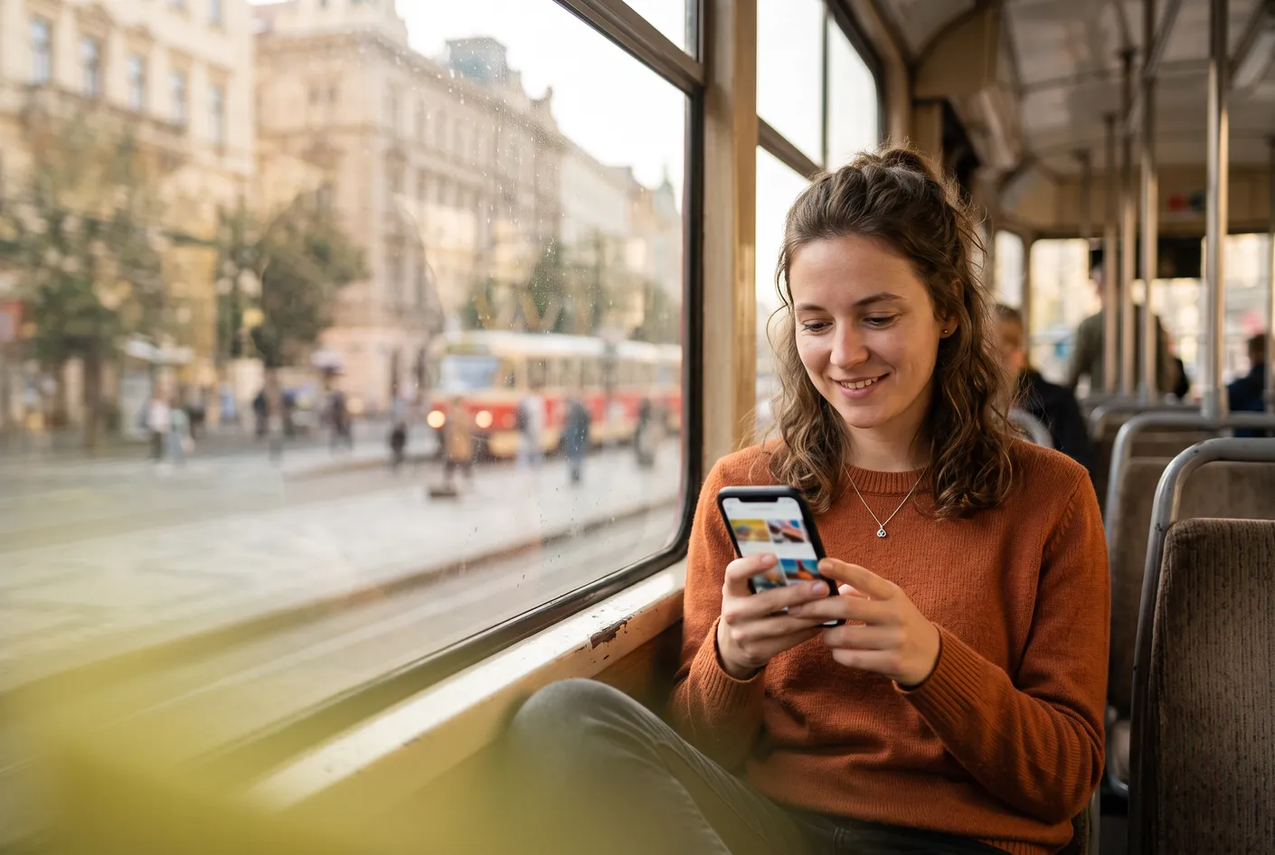 A woman on a morning tram scrolling through recommended articles on her phone