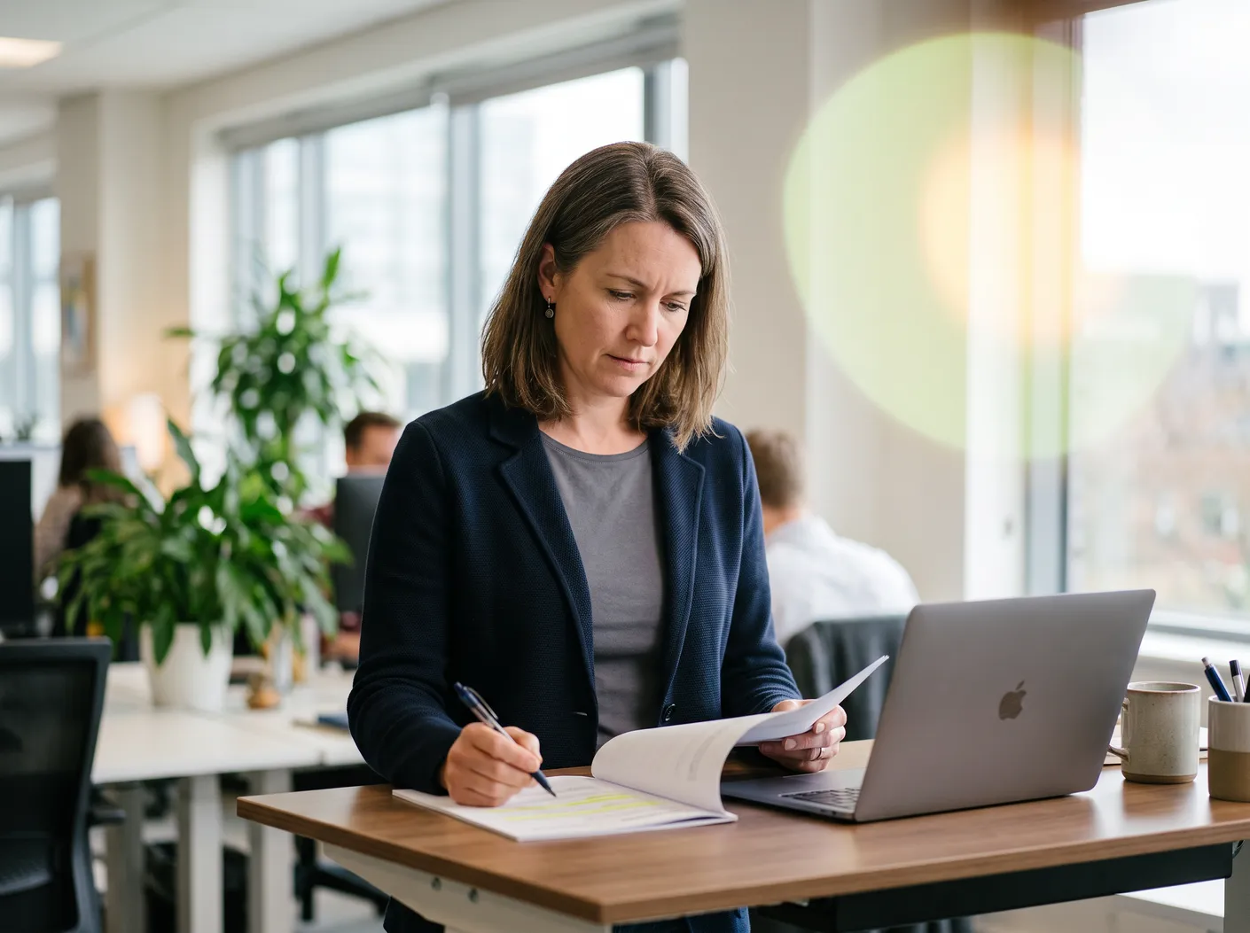 A woman taking notes in a notebook at her laptop – David Zelenka